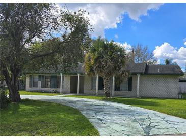 Charming single-story home with a long driveway, white brick, and a columned front porch on a sunny day at 616 N Palm Ave, Kissimmee, FL 34741