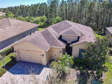 Inviting single-Gathering home featuring a well-manicured lawn, brick driveway, and a spacious three-car garage at 741 Villa Park Rd, Poinciana, FL 34759