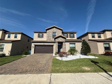 Beautiful two-story home with stone accents, a well-manicured lawn, and a brick paver driveway at 199 Macaulays Cv, Haines City, FL 33844