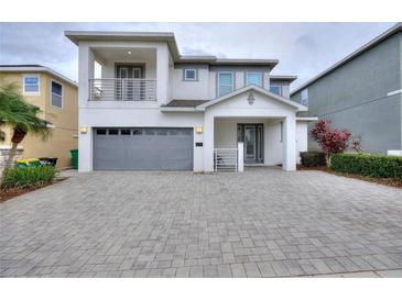 Stunning two-story home featuring a balcony and a two-car garage, complemented by a patterned brick driveway at 7649 Wilmington Loop, Kissimmee, FL 34747