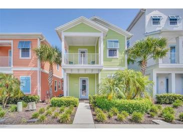 Charming two-story green home with a balcony, complemented by lush landscaping at 8029 Sandy Toes Way, Kissimmee, FL 34747