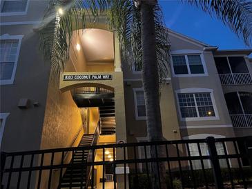 Inviting condo exterior featuring a well-lit entryway and lush palm trees at 8103 Coconut Palm Way # 204, Kissimmee, FL 34747