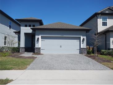 Charming single-Gathering home featuring a gray exterior, gray driveway, and a two-car garage at 1359 Greenfield Loop, Kissimmee, FL 34747