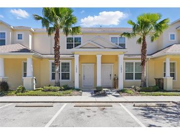 Inviting two-story townhome with a yellow exterior, well-kept landscaping, and prominent palm trees at 1645 Retreat Cir, Clermont, FL 34714