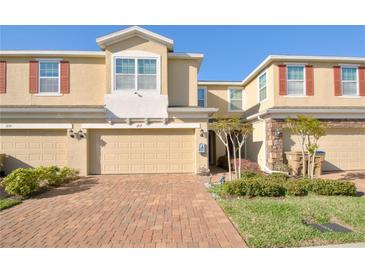 Townhome with two stories, charming curb appeal, beige exterior and a brick driveway at 1737 Kato Way, Kissimmee, FL 34744