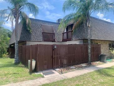 Two-story home featuring a wooden fence, partial brick wall, and complemented by lush landscaping, including palm trees at 1926 Cattleya Dr, Kissimmee, FL 34741