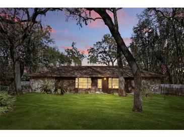 Charming ranch-style home with stone accents, a well-manicured lawn, and mature trees offering shade at 3165 Maple Run, Kissimmee, FL 34744