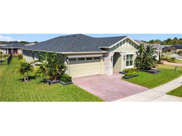 Beautiful single-story home showcasing manicured landscaping and a brick driveway leading to a two-car garage at 3240 Songbird Cir, Harmony, FL 34773