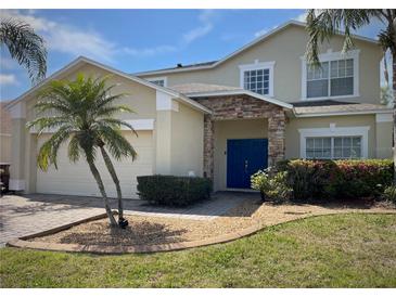 Charming two-story home featuring a stone-accented entrance, blue double doors, and lush landscaping at 4602 Cumbrian Lakes Dr, Kissimmee, FL 34746