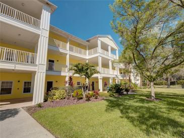 Bright yellow condo building with white trim, balconies, and beautifully landscaped grounds on a sunny day at 709 Lucaya Loop # 1203, Davenport, FL 33897