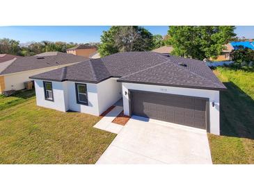 A modern, one-story home featuring a gray roof, a two-car garage, and well-maintained landscaping at 1013 Cannes Dr, Kissimmee, FL 34759