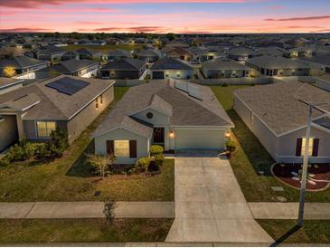 Gorgeous aerial view of a single-Gathering home featuring a manicured lawn in a neighborhood at sunset at 1431 Lassen St, Haines City, FL 33844