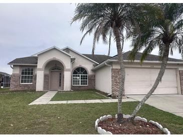Charming single-story home featuring a well-manicured lawn, brick accents, and mature palm trees at 2438 Winfield Dr, Kissimmee, FL 34743