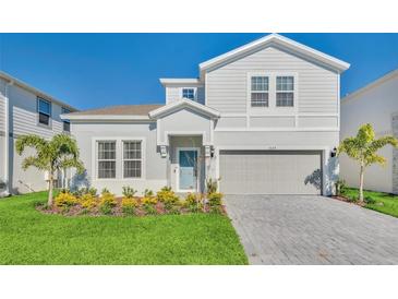 Charming two-story home with landscaped front yard and a two-car garage, painted in light gray at 3624 Lily Ln, Davenport, FL 33897