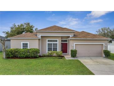 Charming single-Gathering home with a well-manicured lawn and a red front door at 3840 Wood Thrush Dr, Kissimmee, FL 34744