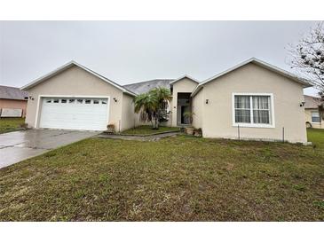 Inviting one-story home featuring an attached two-car garage and a well-maintained front yard with mature landscaping at 466 Peppermill Cir, Kissimmee, FL 34758