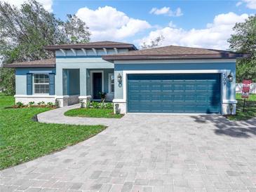 Beautiful one-story home with a paver driveway, a teal garage door, and manicured landscaping at 509 Lakeview Dr, Poinciana, FL 34759