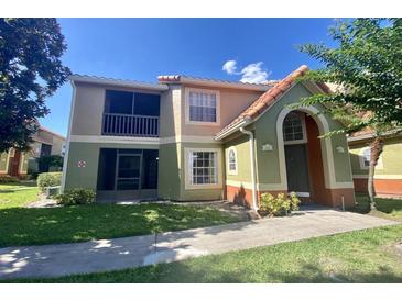 Inviting two-story condo featuring a mix of stucco and tile roof, complemented by lush green landscaping at 445 Fountainhead Cir # 264, Kissimmee, FL 34741