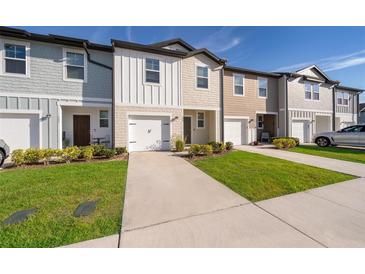 Charming townhomes with colorful facades, well-maintained lawns, and driveways leading to attached garages at 728 Madison Dr, Davenport, FL 33837