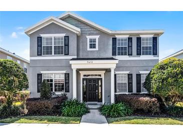 Charming two-story home featuring a well-manicured front yard and black shutters at 7412 Soiree Way, Reunion, FL 34747