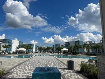Resort-style pool area with cabanas, loungers and palm trees providing a relaxing oasis at 7740 Sandy Ridge Dr # 1, Kissimmee, FL 34744