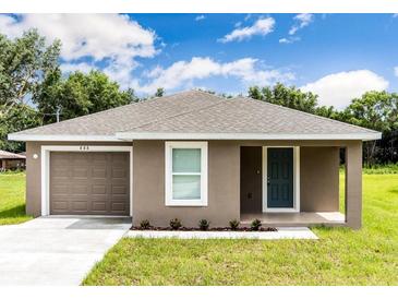 Charming single-story home with a well-manicured lawn, attached garage, and neutral color palette at 214 Kay St, Auburndale, FL 33823