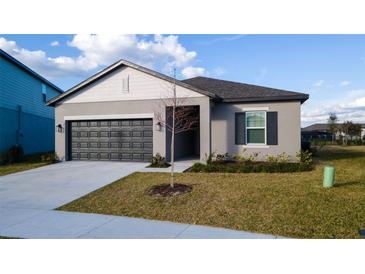 Charming single-story home features a well-manicured lawn, gray exterior, and attached two-car garage at 2166 Derwent Dr, Davenport, FL 33896