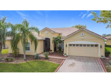 Charming single-story home boasts a tile roof, two-car garage, brick driveway, and lush landscaping with palm trees at 3010 Winding Trl, Kissimmee, FL 34746