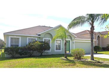 Charming single-story home with a well-maintained lawn, lush landscaping, and a two-car garage at 502 Woodland Creek Blvd, Kissimmee, FL 34744