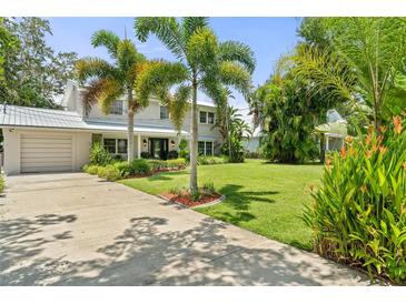 Two-story home with lush landscaping, palm trees, and a metal roof, complemented by a concrete driveway at 6100 Alligator Lake W Shr, St Cloud, FL 34771