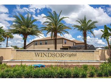 Windsor at Westside community entrance featuring a stone sign, palms, and lush landscaping under a bright, cloudy sky at 8936 Sydney Ave, Kissimmee, FL 34747