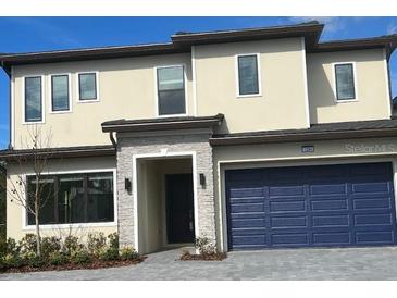 Charming two-story home featuring a stone-accented entrance and a two-car blue garage door at 1294 Butterfly, Davenport, FL 33837