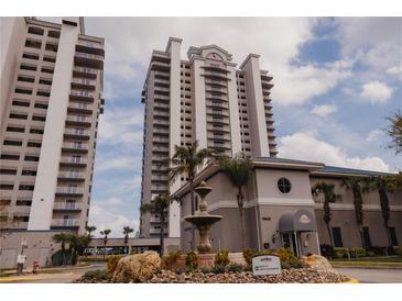Exterior view of a multi-story building with a fountain and landscaping in front under a cloudy sky at 13427 Blue Heron Beach Dr # 1607, Orlando, FL 32821