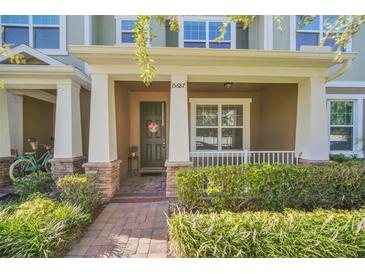 Inviting front porch featuring brick pathway, lush landscaping, and Craftsman-style columns at 15687 Kinnow Mandarin Ln, Winter Garden, FL 34787