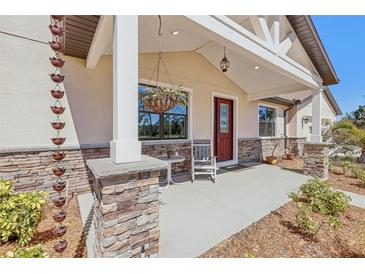 Charming front porch with stone pillars, a hanging plant, and a cozy rocking chair at 3607 Hidden River Ln, Tavares, FL 32778