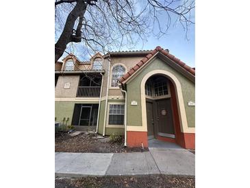 Two-story condo building featuring colorful facades, a red tile roof, and arched entryway at 401 Fountainhead Cir # 155, Kissimmee, FL 34741