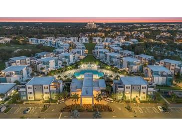 Stunning aerial view of modern community with a large pool and lush landscaping at dusk at 7760 Sandy Ridge Dr # 108, Reunion, FL 34747