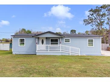 Charming single story home with a white porch railing, blue siding and green front lawn at 3139 Morning Light Way, Kissimmee, FL 34744