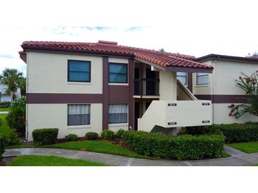 Two story condominium building showing a terracotta roof and lush landscaping at 3214 Candle Ridge Dr # 201, Orlando, FL 32822