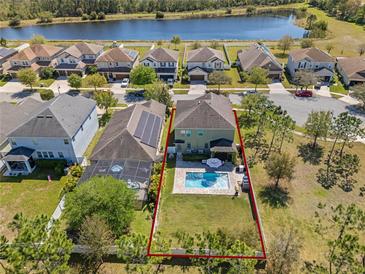 Aerial view of a home with a pool, a large yard, and a view of the lake at 3384 Cordgrass Pl, Harmony, FL 34773