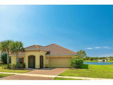 Charming home featuring a tile roof, manicured lawn, and inviting front entrance by a tranquil lake at 3818 Carrick Bend Dr, Kissimmee, FL 34746