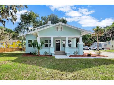 Charming bungalow features a light blue exterior, inviting front porch and neatly manicured landscaping at 415 S 9Th St, Leesburg, FL 34748