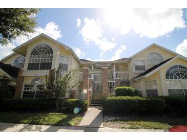 Two-story condo with a brick stairway, trimmed bushes, and bright yellow siding at 5004 Laguna Bay Cir # 54, Kissimmee, FL 34746