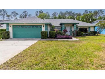 Inviting single-story home featuring a well-manicured lawn, a teal garage door, and trimmed landscaping at 7794 Indian Ridge S Trl, Kissimmee, FL 34747