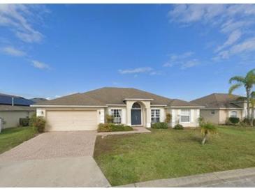Charming single-story home with a well-maintained lawn, brick driveway, and two-car garage at 152 Moscato Dr, Davenport, FL 33897