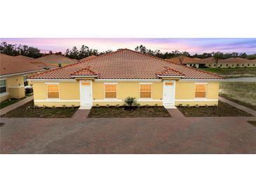 Charming single-story villa with red tile roof, yellow exterior, and well manicured landscaping at 1787 Coriander Dr, Kissimmee, FL 34759