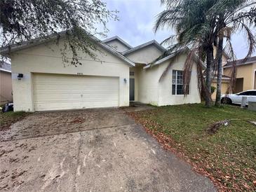 Exterior of one-story home with attached garage, neutral stucco siding, and lawn at 4406 Hidden Meadow Dr, Kissimmee, FL 34746