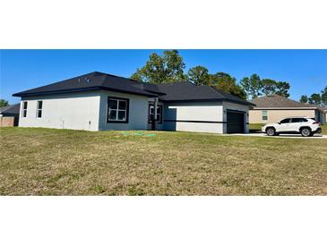 Lovely single-story home with neutral stucco, a dark roof, a dark two-car garage, and well-manicured yard at 4491 Sw 151 St, Ocala, FL 34473