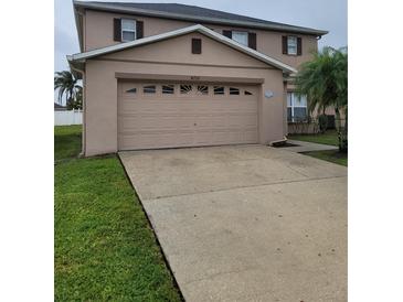 Exterior view of the two-car garage with a long concrete driveway and well-manicured lawn at 4710 Willoughby St, Kissimmee, FL 34758