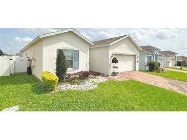 Charming single-Gathering home with manicured lawn, colorful landscaping, and brick paved driveway at 486 Disa Dr, Davenport, FL 33837